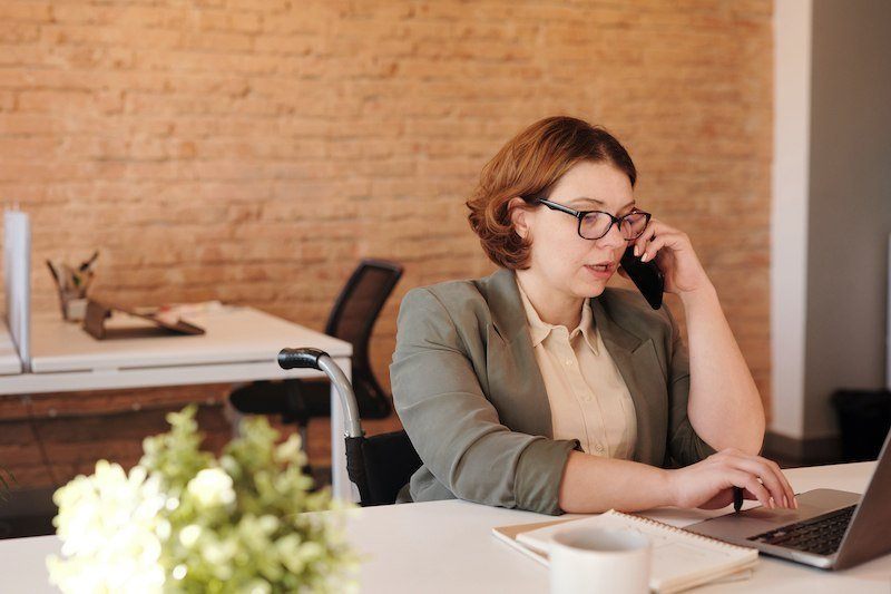 Bild: Frau am Laptop und mit Telefon in der Hand